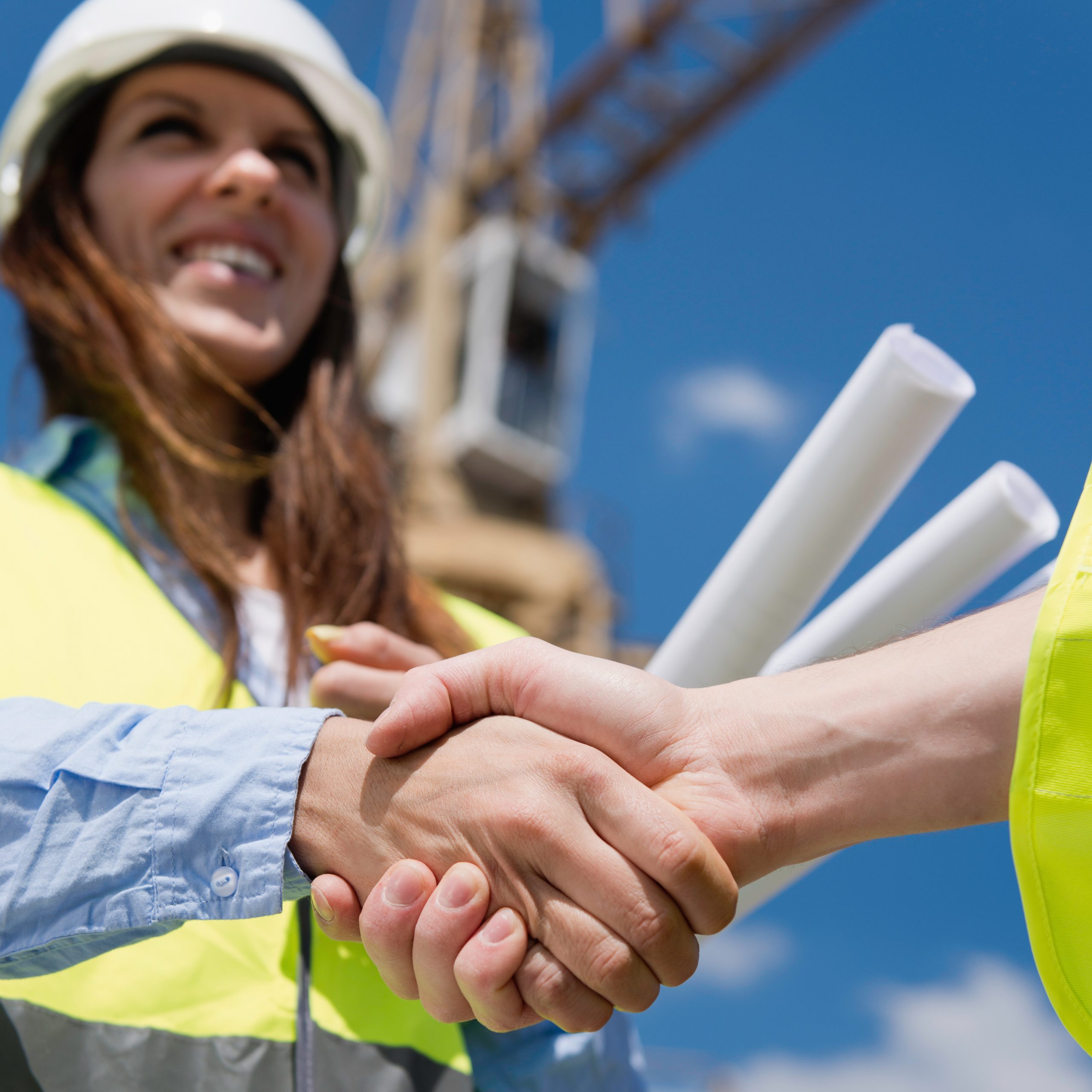 Architect at construction site, shaking hands with engineer